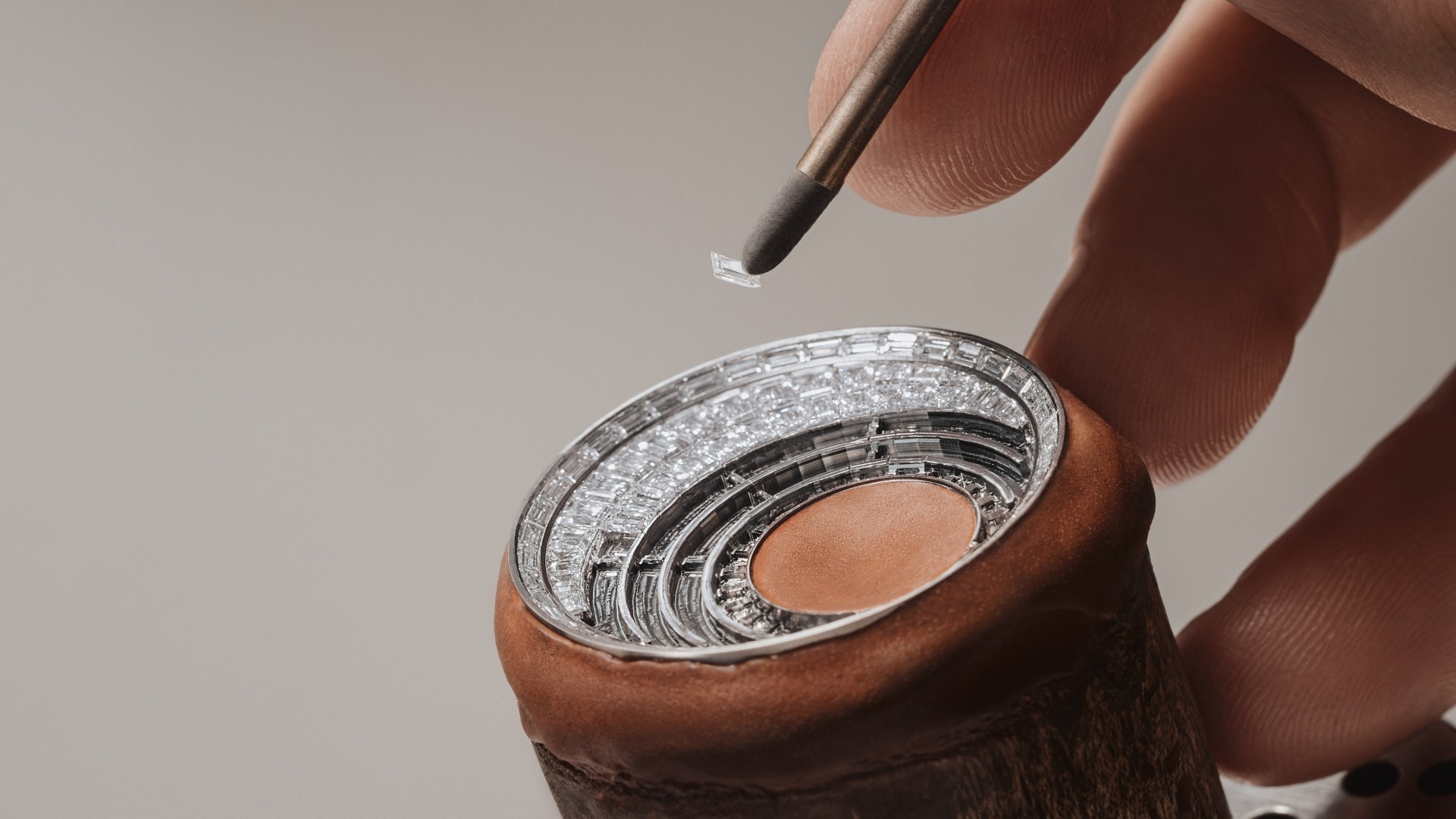 珠宝商用尖头工具将钻石镶嵌在手表部件的同心圆上。