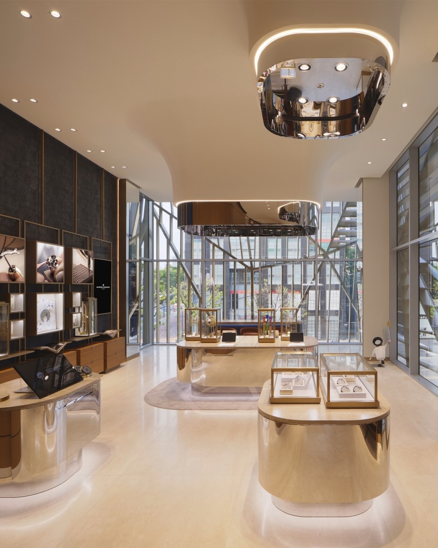 Inside the Vacheron Constantin boutique in Seoul. It features a central island in soft gold tones and large windows filled with natural light.