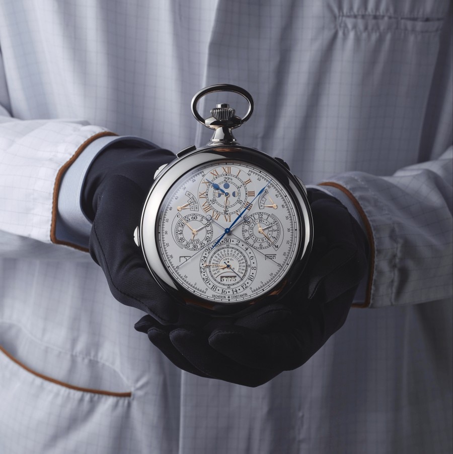 Hands holding the head of a large clock with complex details for telling time