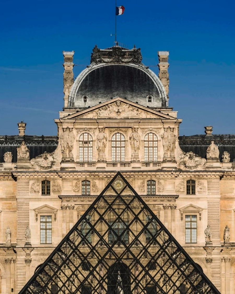Fasade of the Louvre Museum with the glass pyramid in front.