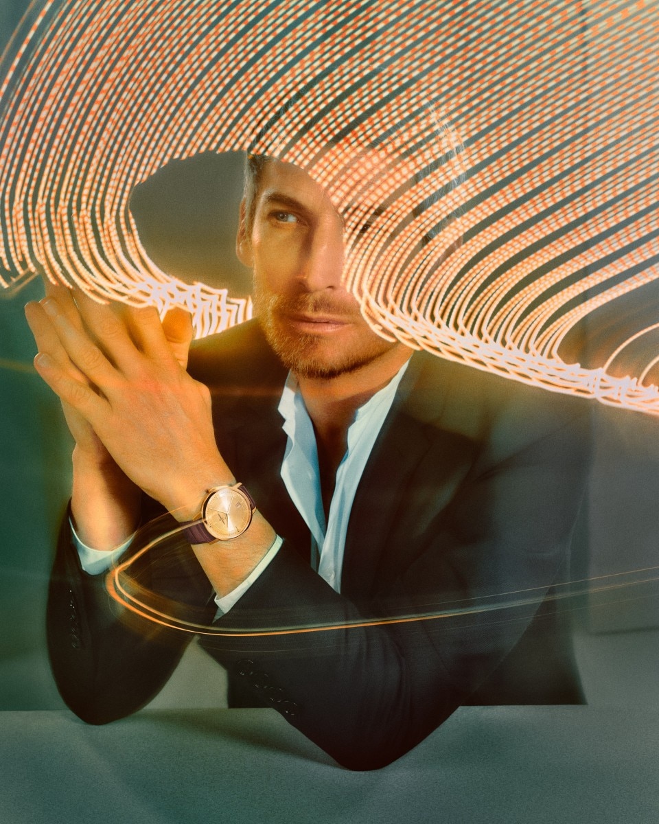 A man in a suit posing with his hands together, wearing a Vacheron Constantin watch.
