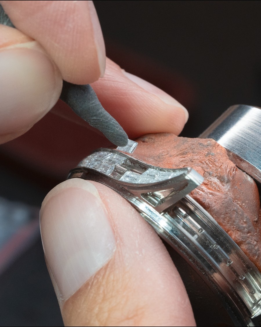 Precision setting of diamonds onto a watch case using a fine tool.