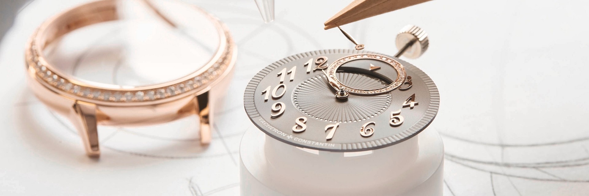 Zerlegte Komponenten einer Vacheron Constantin-Uhr, darunter Uhrengehäuse, Zifferblatt und Zeiger, auf hellem Hintergrund angeordnet.
