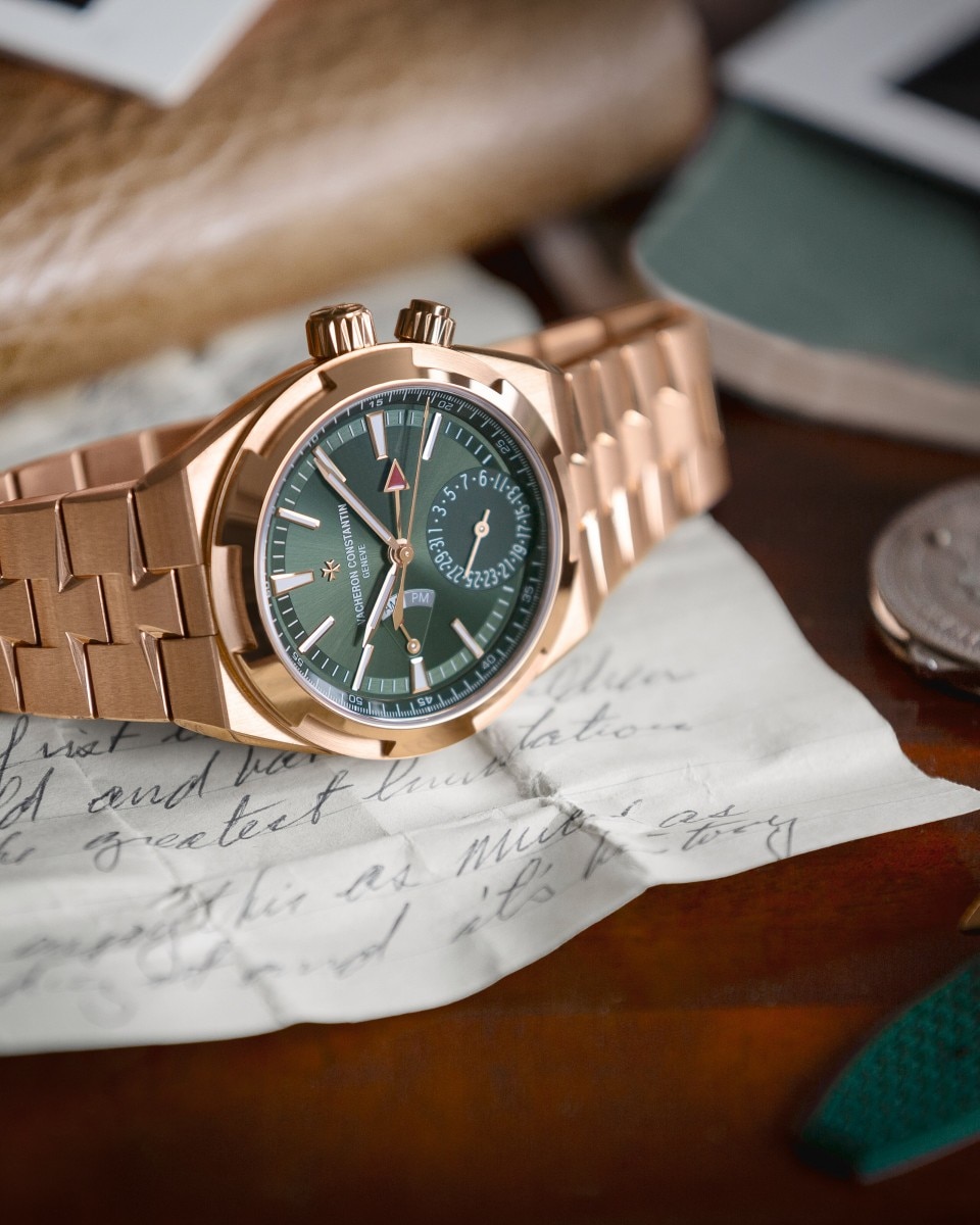 Primo piano di un cronografo Vacheron Constantin con quadrante verde e bracciale in oro rosa, poggiato su un foglio di carta piegato.