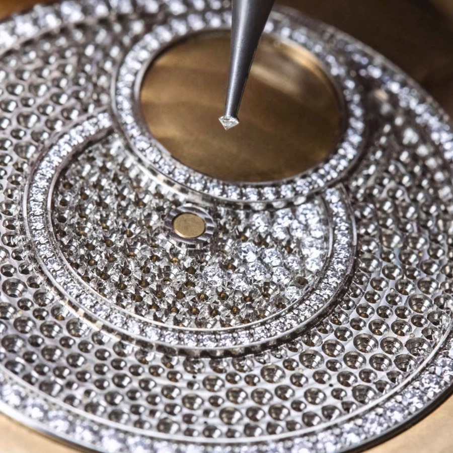 Diamond-setting process on a circular watch component using a precision tool.