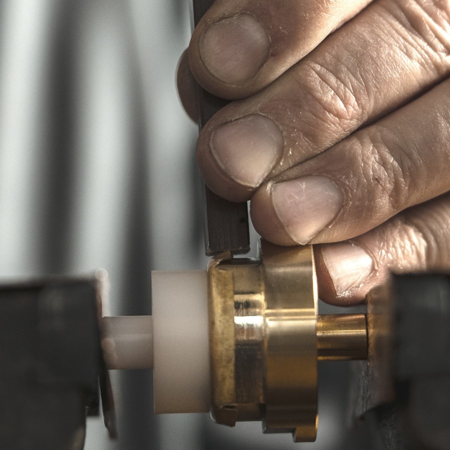 Hands polish the case of a gold watch
