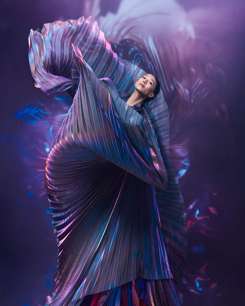 一幅充满戏剧性的画面:一位身着飘逸宽大紫色长袍的女人正在翩翩起舞。