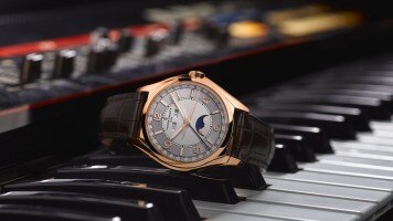 A diamond-set luxury watch with a moonphase display placed on piano keys.