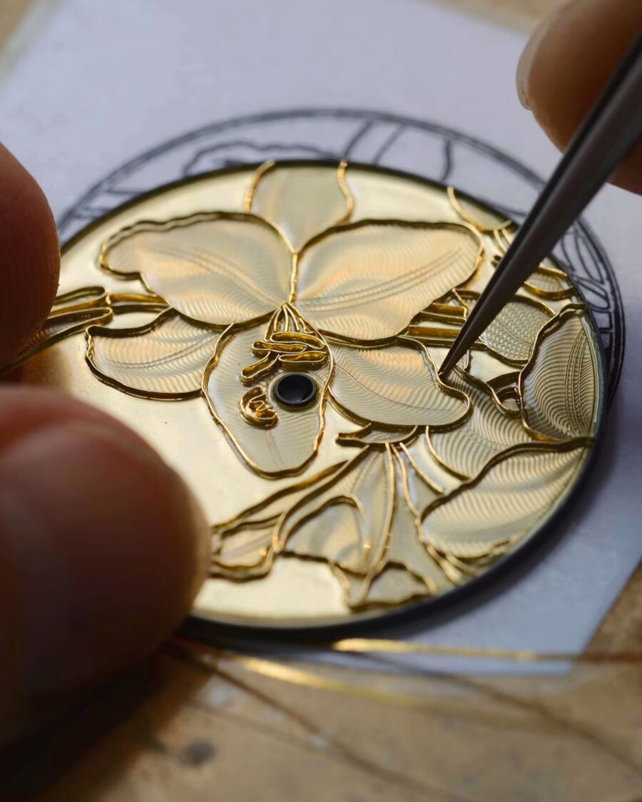 Incisione a mano di un motivo floreale sul quadrante di un orologio.