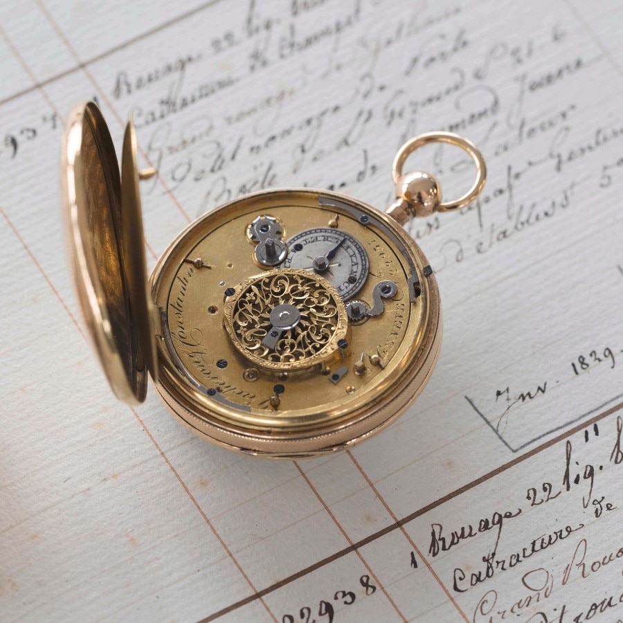 an open circular gold watch on the left is the cover, and on the right is the mechanism