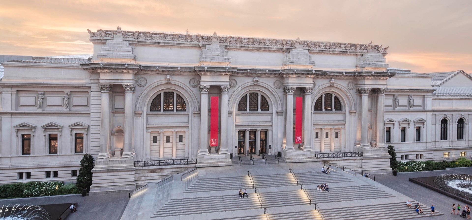 Front entrance of  The Met with red banners and classical architecture.